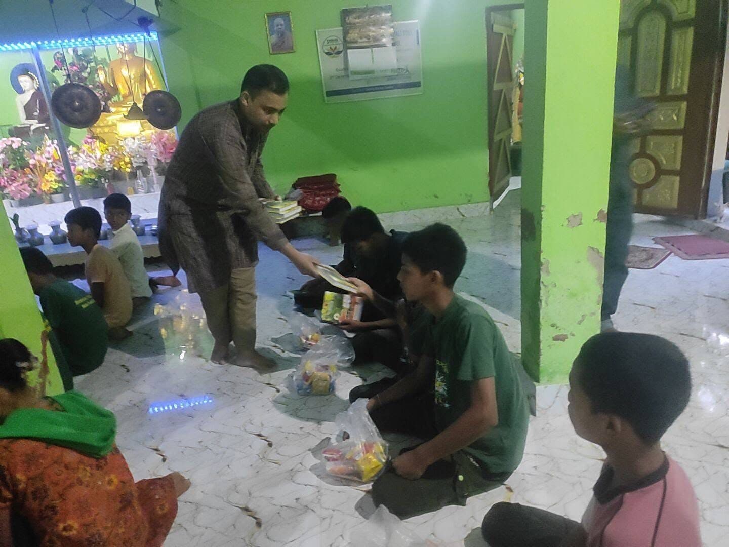 Saku Barua is giving books to students.